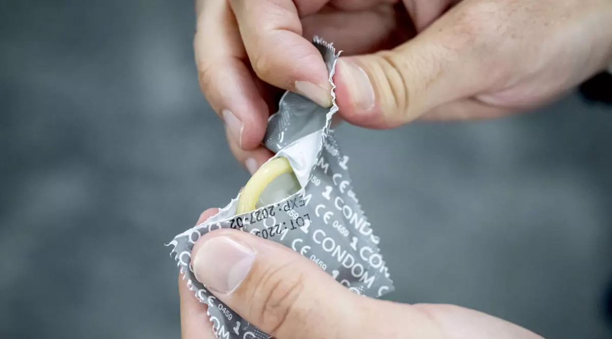 Un bărbat ruoe folia unui prezervativ