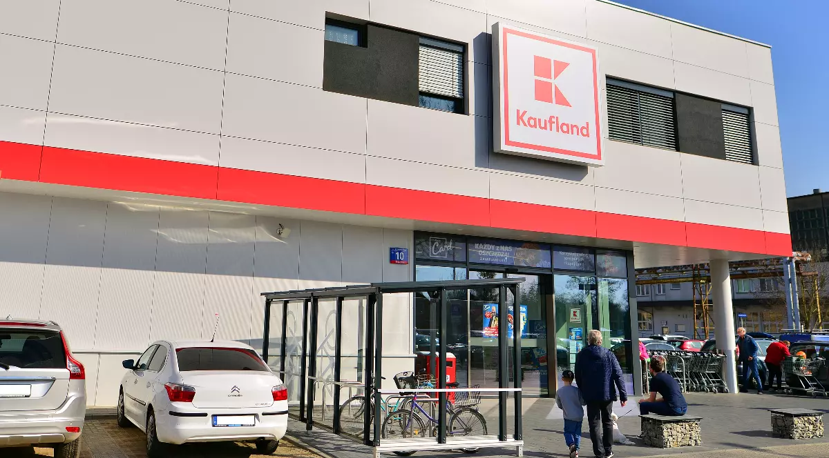 Intrarea într-un magazin Kaufland, mașinile sunt parcate în fața supermarketului