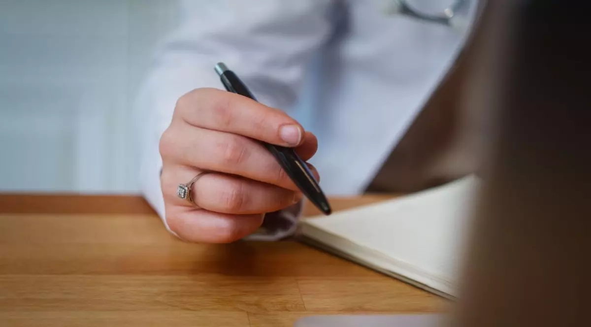 O doctoriță ține un pix în mâna dreaptă, în timp ce consultă o agendă