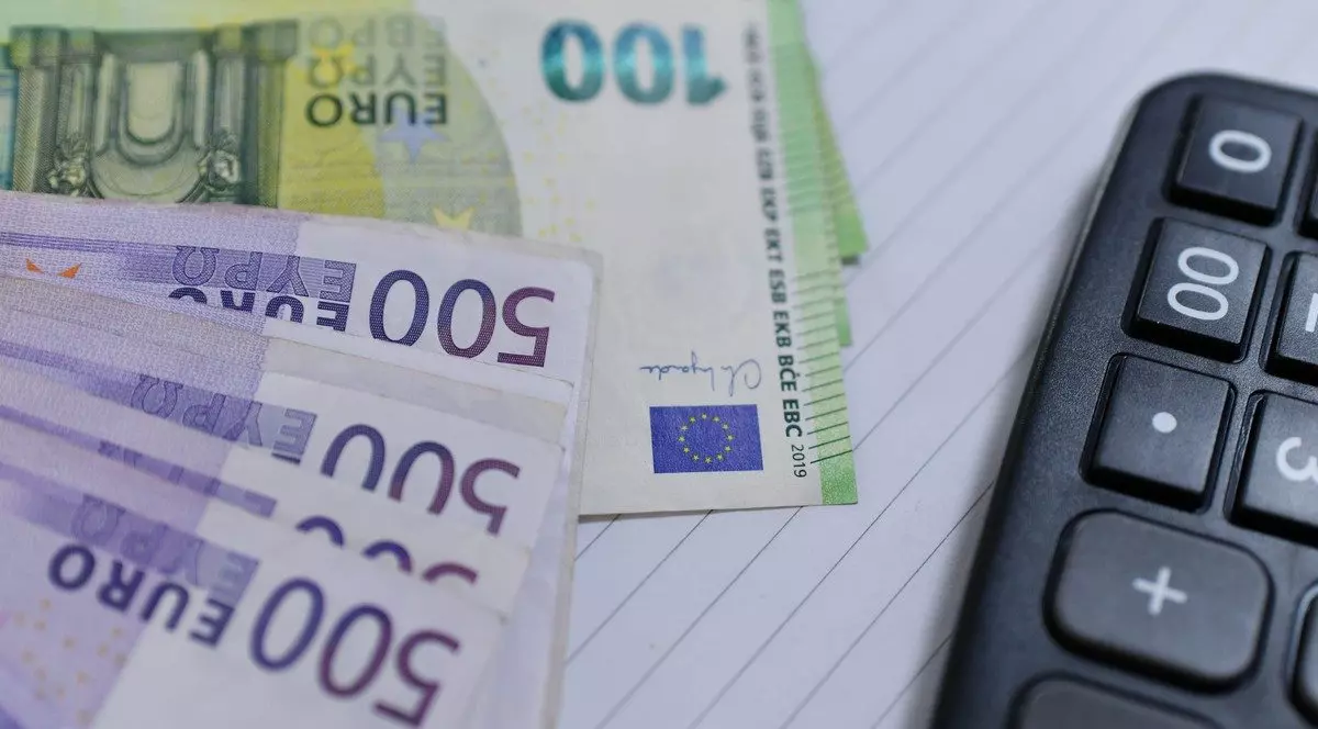 Bancnote de 500 și 100 de euro așezate în evantai, alături de un calculator