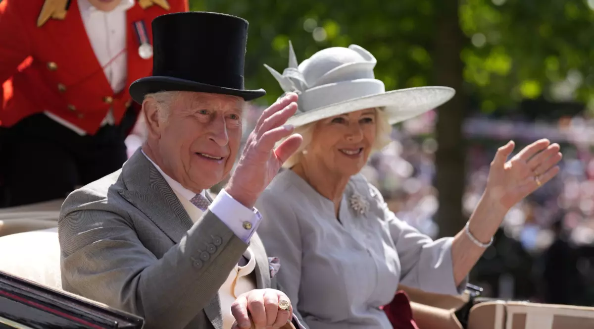 Regele Charles al III-lea și Camilla, în timpul unui eveniment oficial în Marea Britanie, într-o trăsură, în timp ce fac cu mâna publicului