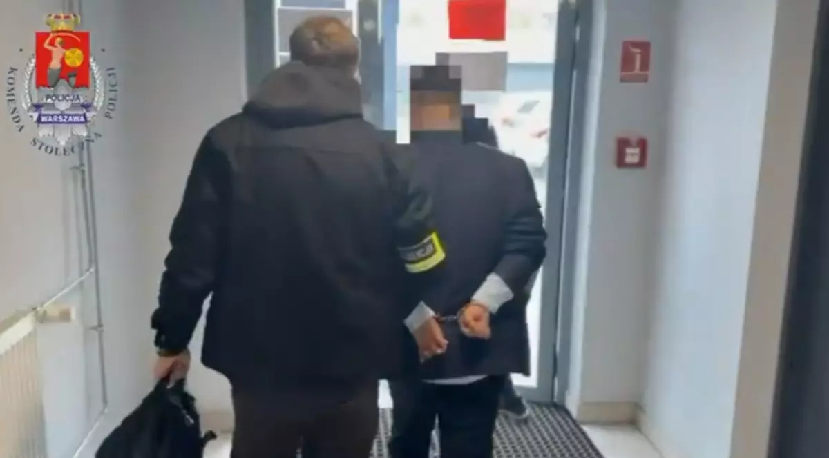 Un bărbat care este ținut cu mâinile la spate de un polițist, spre ieșire