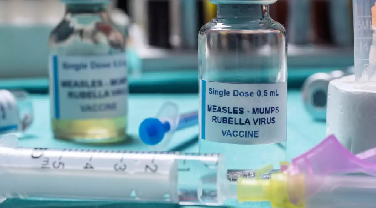 Pe o masă sunt două doze de vaccin ROR si o seringa. Dr. Sandra Alexiu despre rujeola si o complicatie care paralizeaza