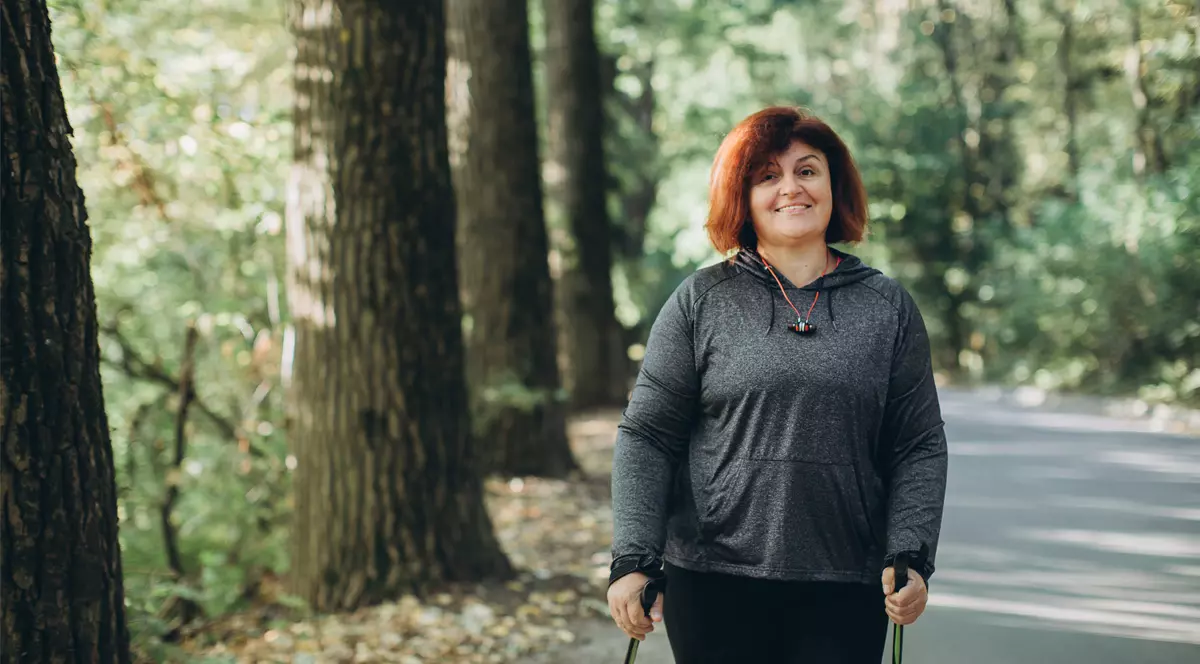 O femeie pe alee in parc mergand in baston. Scleroza multipla in Romania