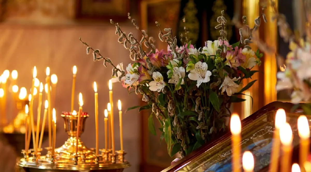 Mesaje de Florii 2026 - cele mai frumoase urări de Florii - Imagine cu un sfeşnic cu lumânări, o icoană şi o vază cu flori, într-o biserică ortodoxă, de Florii
