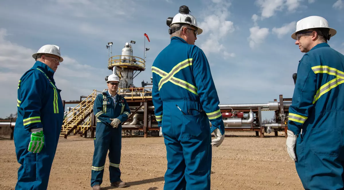 Muncitori petroliști îmbrăcați înalbastru cu căști albe pe ca