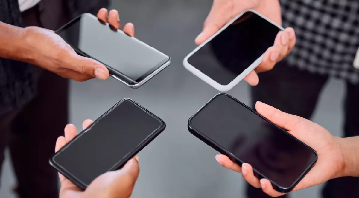 Patru persoane țin telefoane mobile în mână. Ecranele dispozitivelor sunt goale.