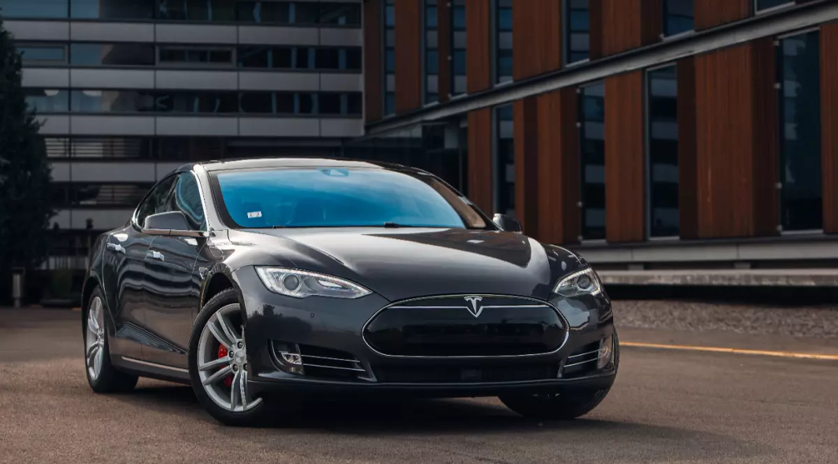 O mașină Tesla neagră parcată în fața unei clădiri de birouri