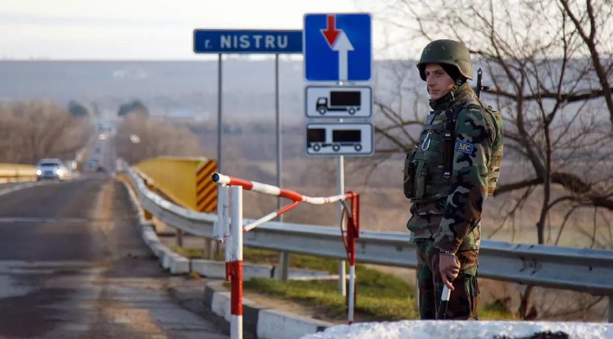 Un soldat cu cască și pușcă pe marginea unei șosele, în Transnistria, la grnaița cu Republica Moldova