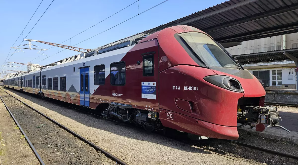 Imaginea prezintă un tren modern Alstom Coradia Stream, aflat în stație, cu un design aerodinamic și culori roșu-alb. Garnitura sugerează modernizarea transportului feroviar și introducerea unor condiții mai confortabile pentru călători.