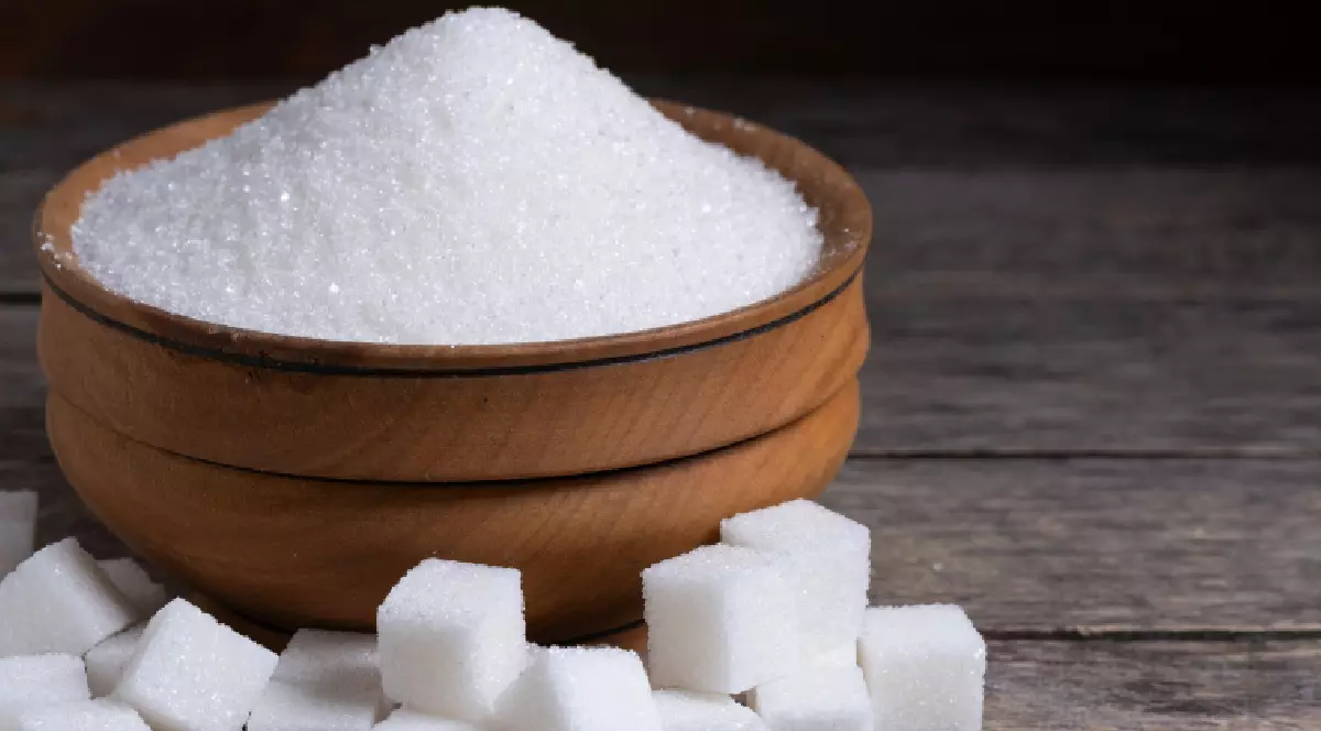 Zahăr într-un bol, alături de cuburi de zahăr pe masă