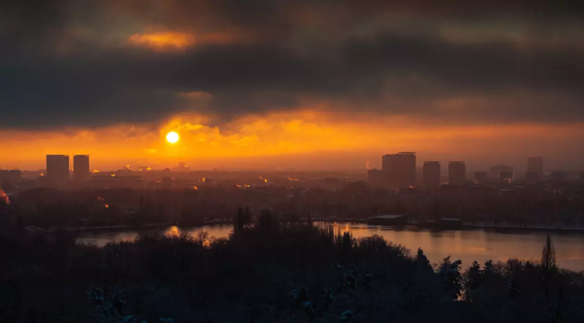 Apusul de soare în București, cerul este înnorat și lumina este portocalie peste cateva clădiri de birouri