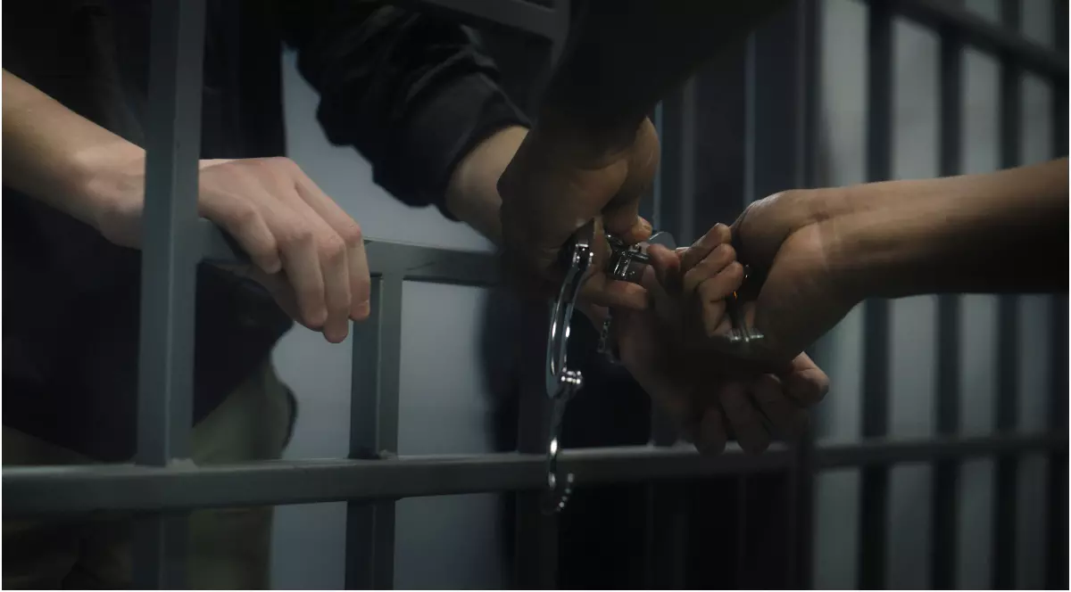 Un bărbat aflat în spatele gratiilor căruia i se deschid cătușele
