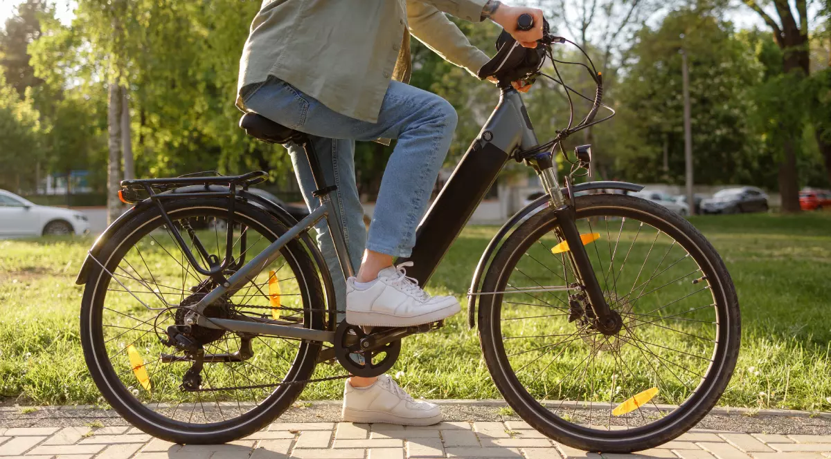 Un tânăr, pe o bicicletă electrică, plimbându-se într-un parc.