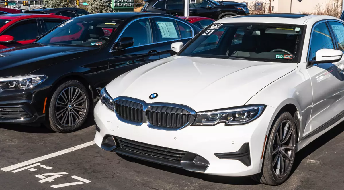 Mai multe automobile BMW sunt expuse într-un parc auto, pregătite pentru vânzare. Imaginea ilustrează piața mașinilor second-hand și procesul de achiziție a unui vehicul de la un dealer auto.