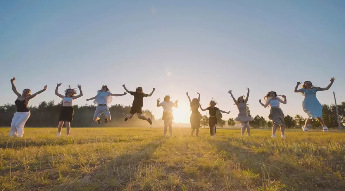 Când începe vacanța de vară 2026 - Mai mulți tineri sar de bucurie aer pe un câmp la apus
