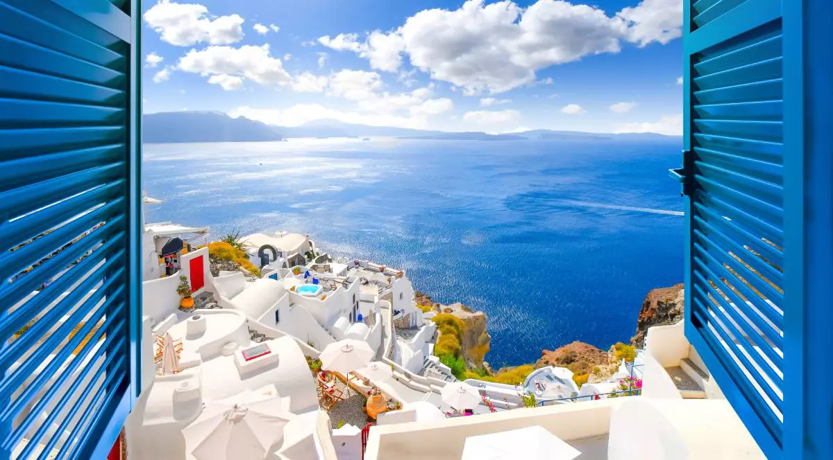Case albe și obloane albastre în Oia, Santorini, zonă mediteraneană, unde arhitectura tradițională ajută locuințele să rămână mai răcoroase în timpul caniculei.
