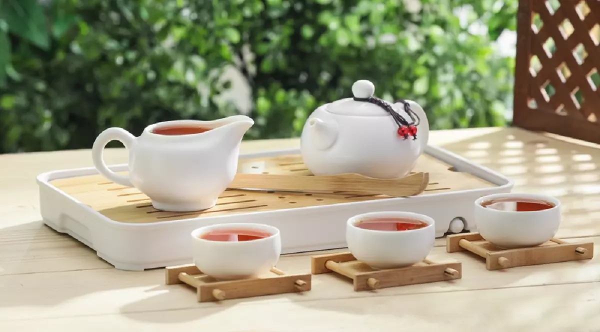 Istoria fascinantă a ceaiului: De la medicament la ritual social - Imagine cu trei ceşti de cafea, un ceainic, o chisea, aşezat pe o masă