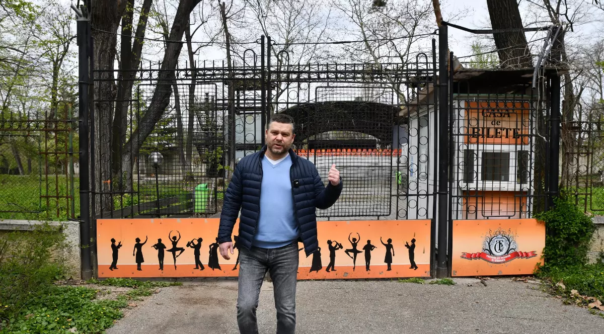 Ciprian Ciucu este fotografiat în fața teatrului de vară din Parcul Herăstrău, în timp ce indică spre zona aflată în spatele său. Imaginea surprinde starea actuală a obiectivului, care urmează să intre într-un proces de reabilitare și modernizare.