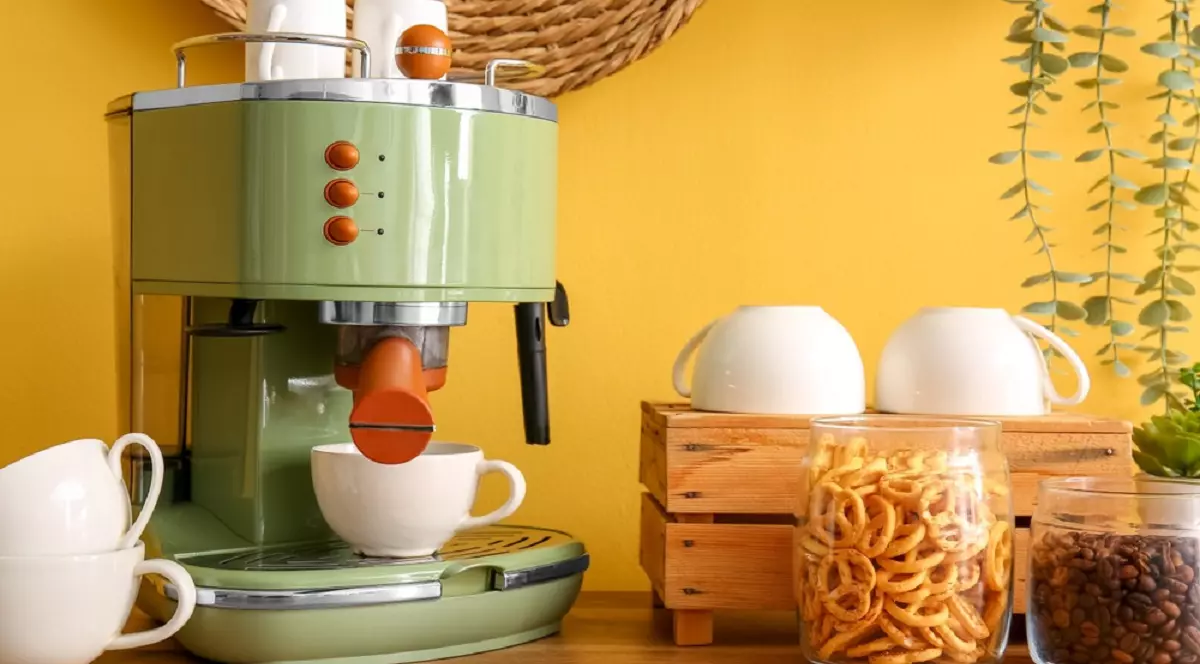 Colțul de cafea: cum să transformi bucătăria într-o cafenea artizanală acasă - Espressor de cafea retro, de culoare verde-fistic, pe un blat de lemn, lângă borcane cu covrigei și boabe de cafea