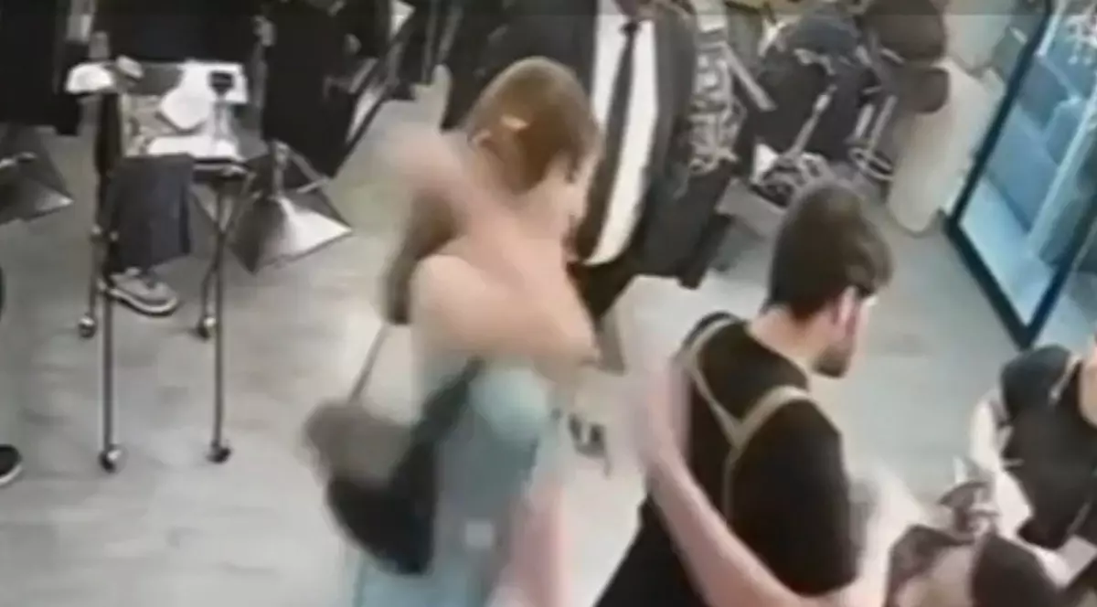 O femeie într-un salon, care ridică mâna asupra unui bărbat îmbrăcat în negru