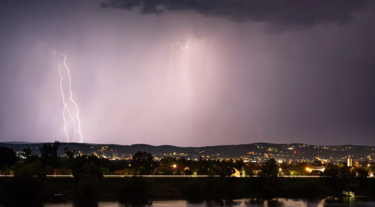 Fulgere în timp ce luminează cerul deasupra unui sat din România, în timpul unei furtuni
