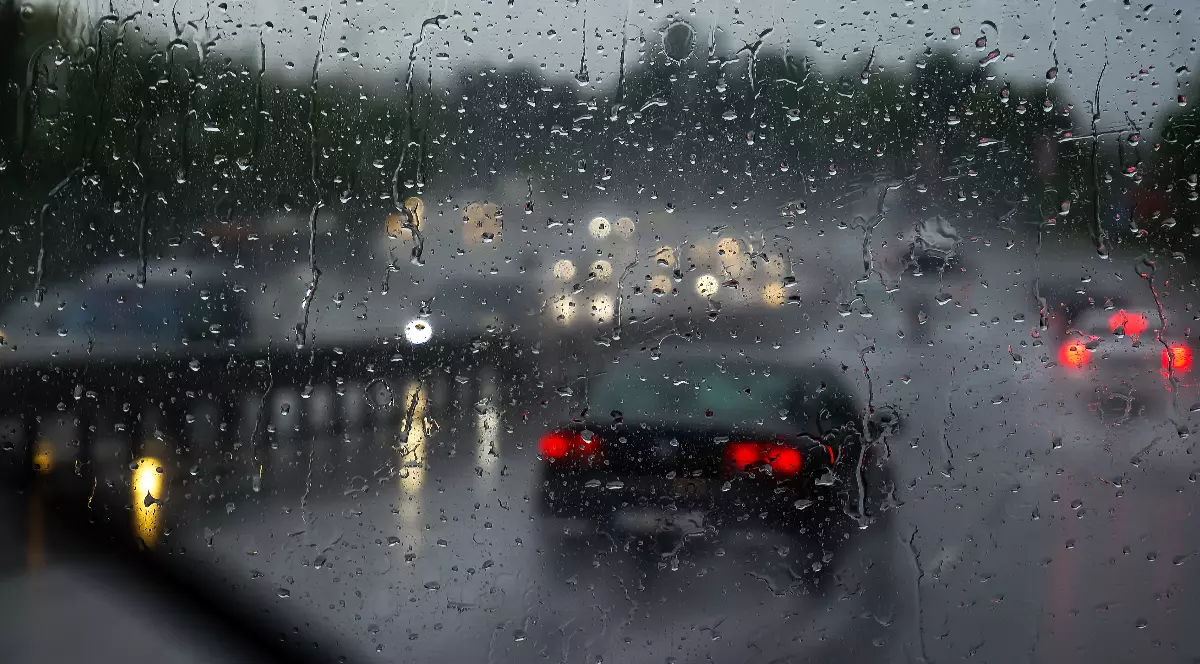 Mașinile în timp ce circulă pe o șosea din România, în timpul unei furtuni puternice. Copacii din fundal sunt înclinați de rafalele vântului și vizibilitatea este redusă din cauza ploii torențiale