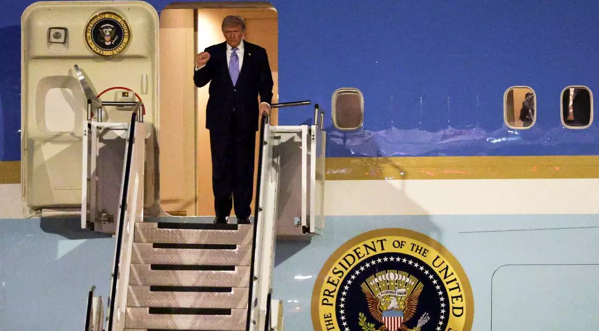 Donald Trump ridică mâna dreaptă cu pumnul strâns pe scara avionului, la sosirea în China, 13 mai 2026