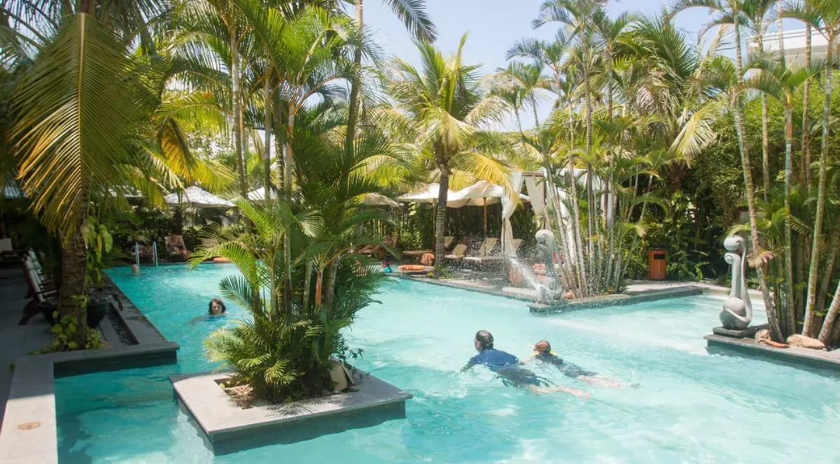 Hotelul și Spa-ul chiar în afara orașului vechi din Hoi An, pe coasta centrală a Vietnamului, piscina cu apa limpede, palmieri, un tata inoata cu copilul sau