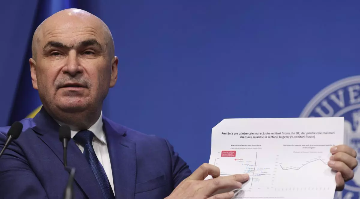 Ilie Bolojan arată un tabel în timpul unei declarații de presă.