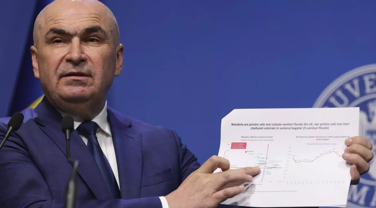 Ilie Bolojan arată un tabel în timpul unei declarații de presă.