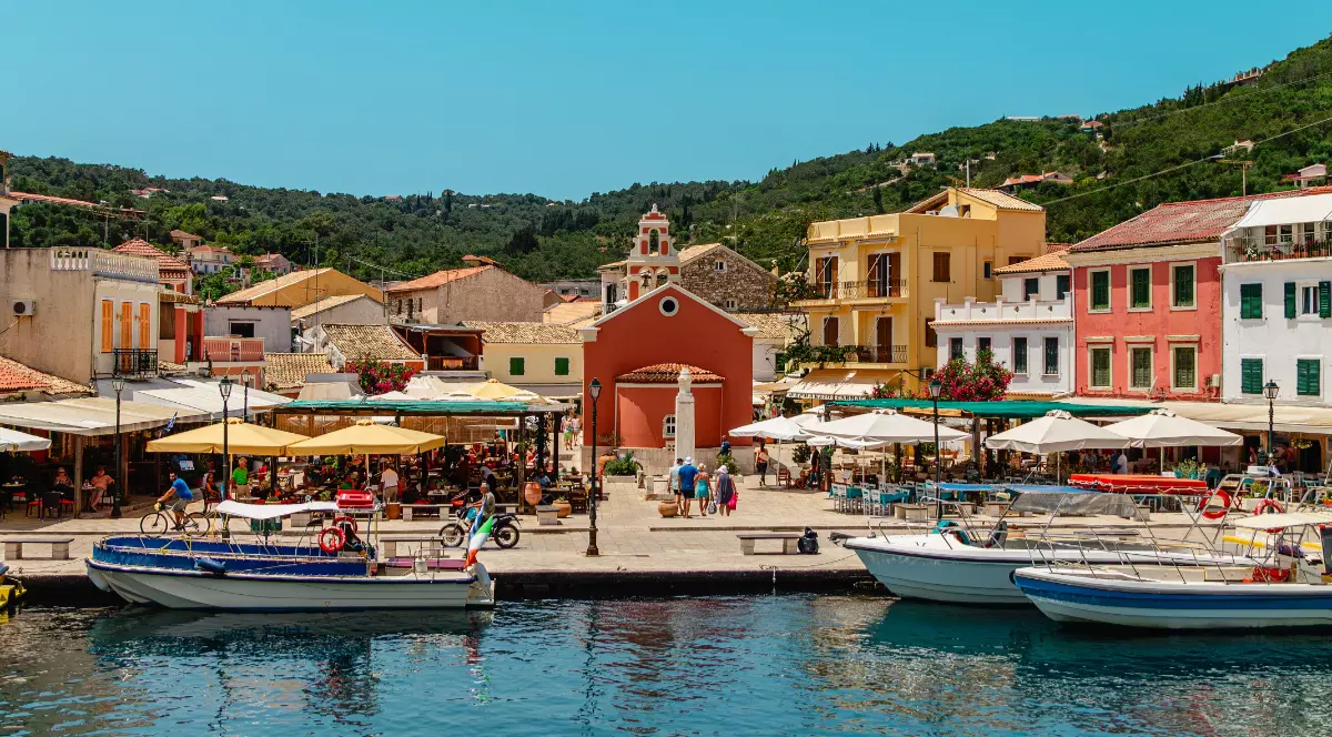 Insula Paxos din Grecia, casele de la malul mării sunt colorate, în port sunt deja trase bărci pentru excursii în jurul insulei