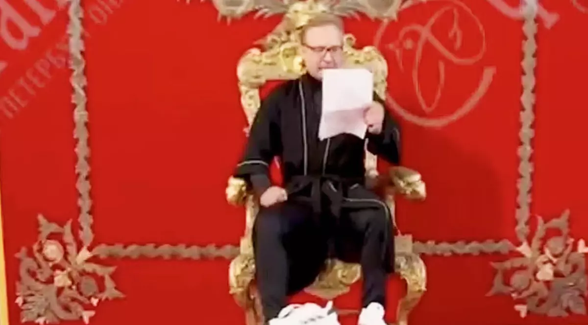 Akeksandr un bărbat îmbrăcat în negru pe un tron cu niște documente în mână.