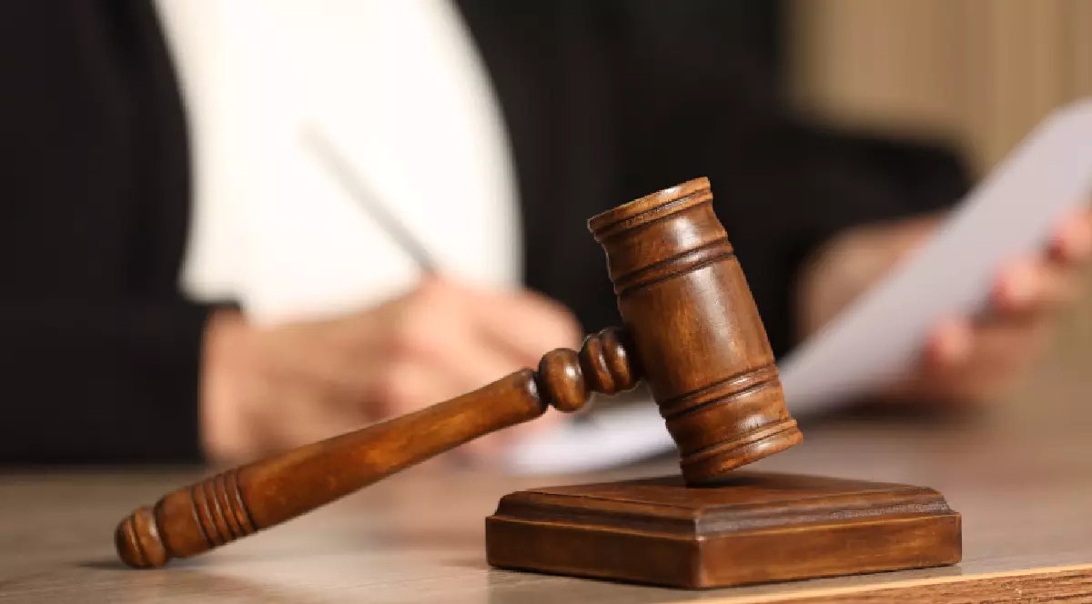Un judecător se uită pe niște documente, iar în fața lui se află un „ciocan de justiție”