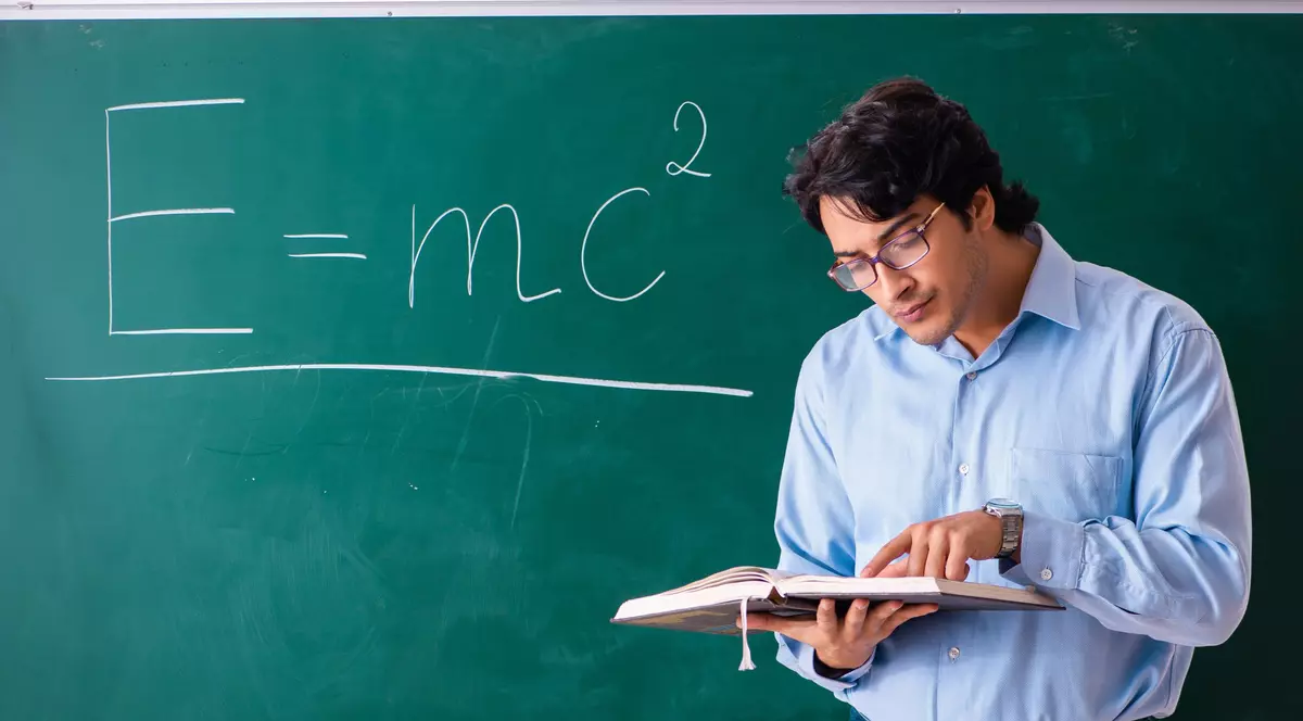 Profesor în cămașă la tablă, unde este scrisă ecuația E=mc2 din fizică