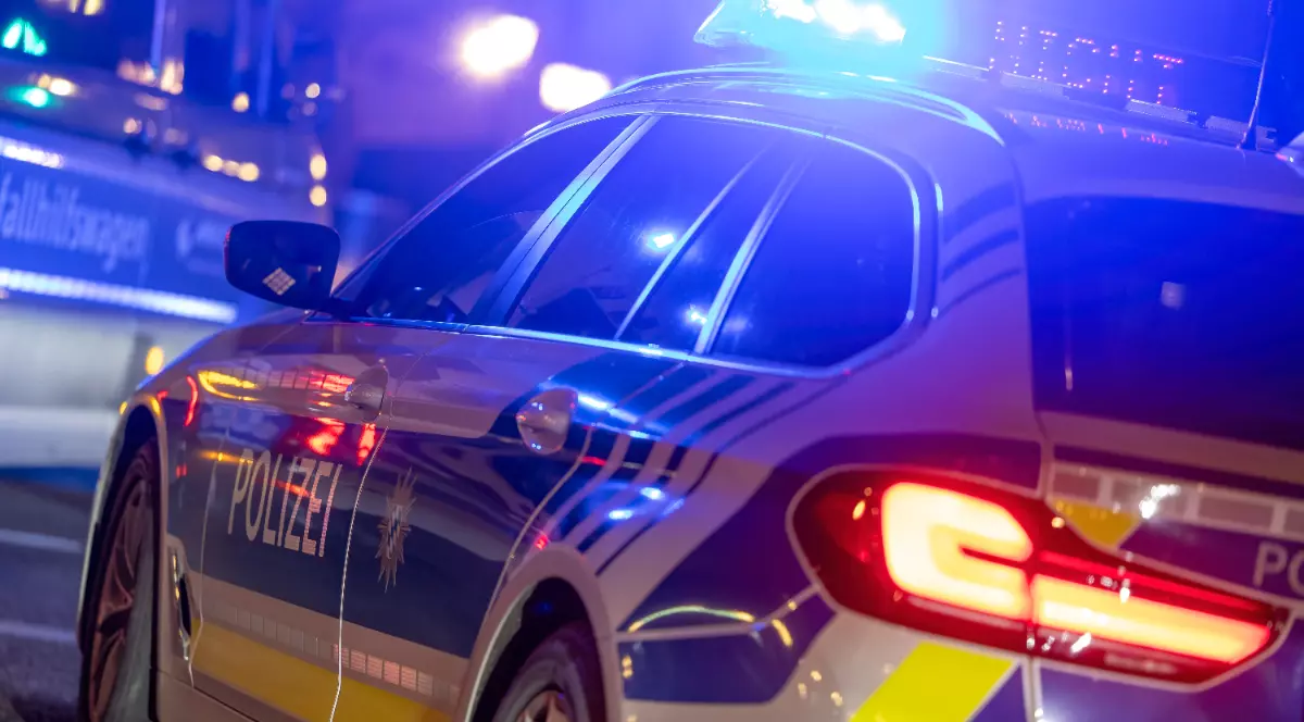 O mașină de Poliție din Germania, cu autocolante albastre și girofarurile pornite, în timp ce merge la o intervenție