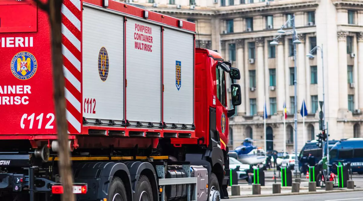 O mașină de pompieri, din cadrul Inspectoratului pentru Situații de Urgență București-Ilfov, pe o stradă din București, cu o clădire pe fundal