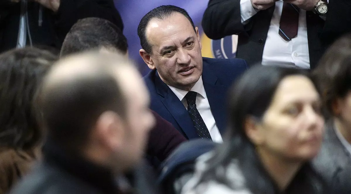 Un barbat in costum este inconjurat de alti oameni