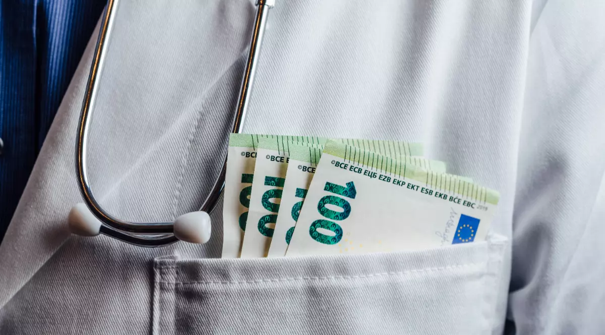 Bancnote de 100 de euro în buzunarul unui halat alb, purtat de un doctor.