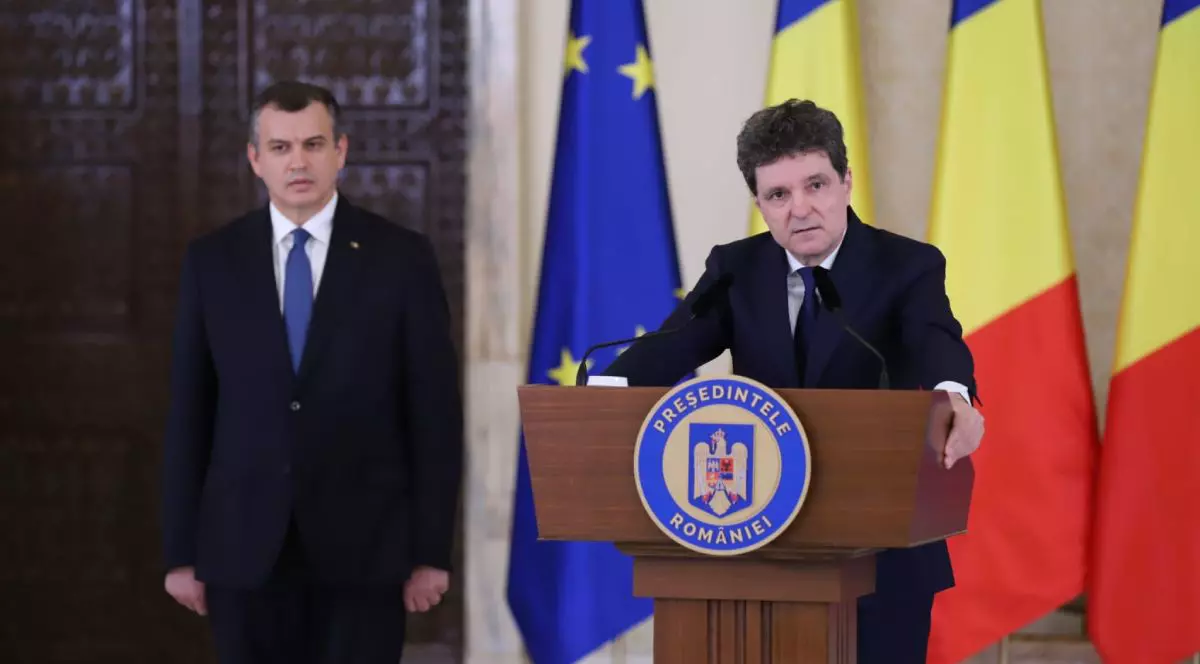 Președintele Nicușor Dan îmbrăcat cu un costum negru, la pupitrul de la Administrația Prezidențială, alături de Eugen Tomac, în stânga sa, îmbrăcat în costum negru, cămașă albă și cravată albastră, iar pe fundal steagurile României și Uniunii Europene