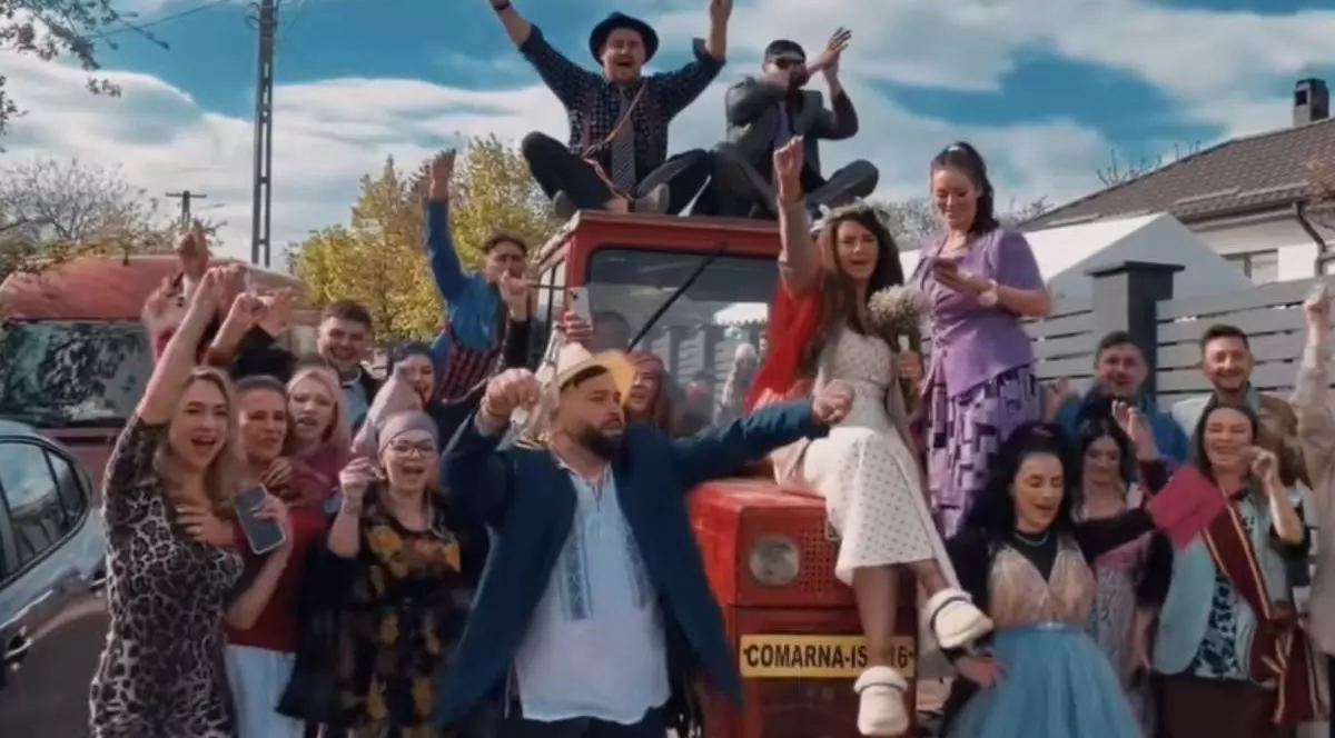 Mirii și mai mulți participanți dansează și se bucură în jurul unui tractor roșu, la petrecerea de după nuntă din Comarna, Iași, organizată în stilul anilor 2000.
