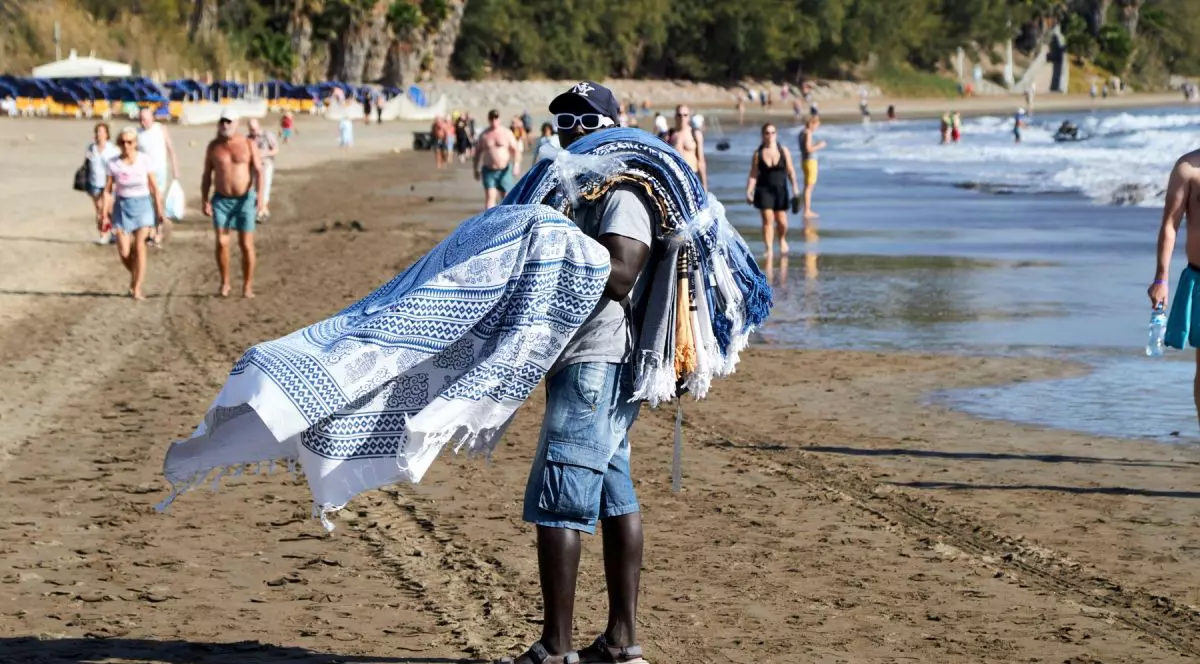 Un bărbat african vinde prosoape de baie pe plaja Maspalomas din Insulele Canare