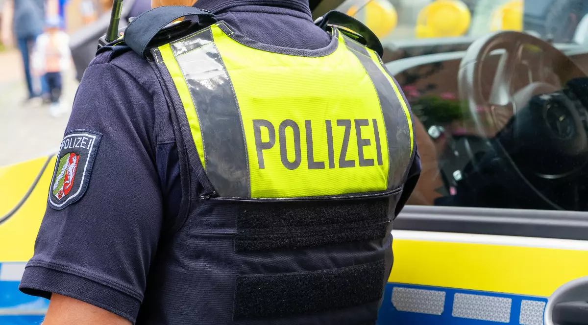 Un polițist din Germania care stă cu spatele lângă o mașină de poliție.