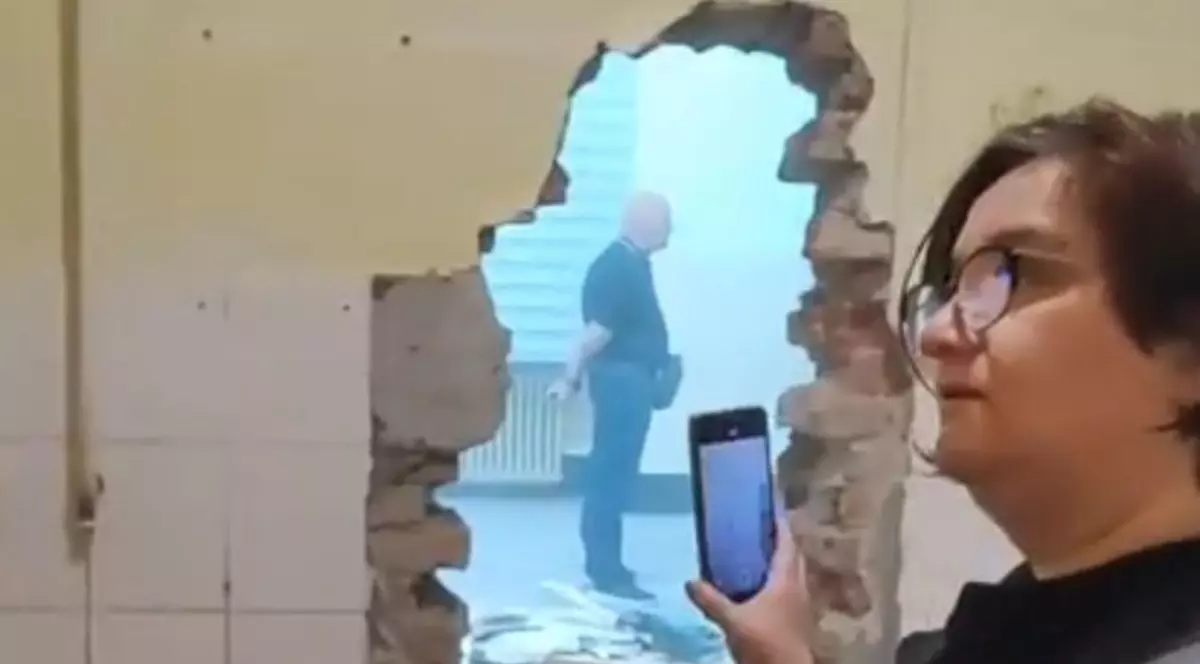 O femeie care filmează un zid spart dintr-o biserică din Oradea