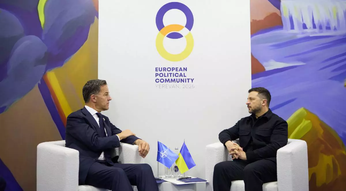 Mark Rutte îmbrăcat într-un costum de culoare închisă, stând pe un fotoliu alb față în față cu Volodimir Zelenski, care poartă o tunică neagră, la Erevan, în mai 2026
