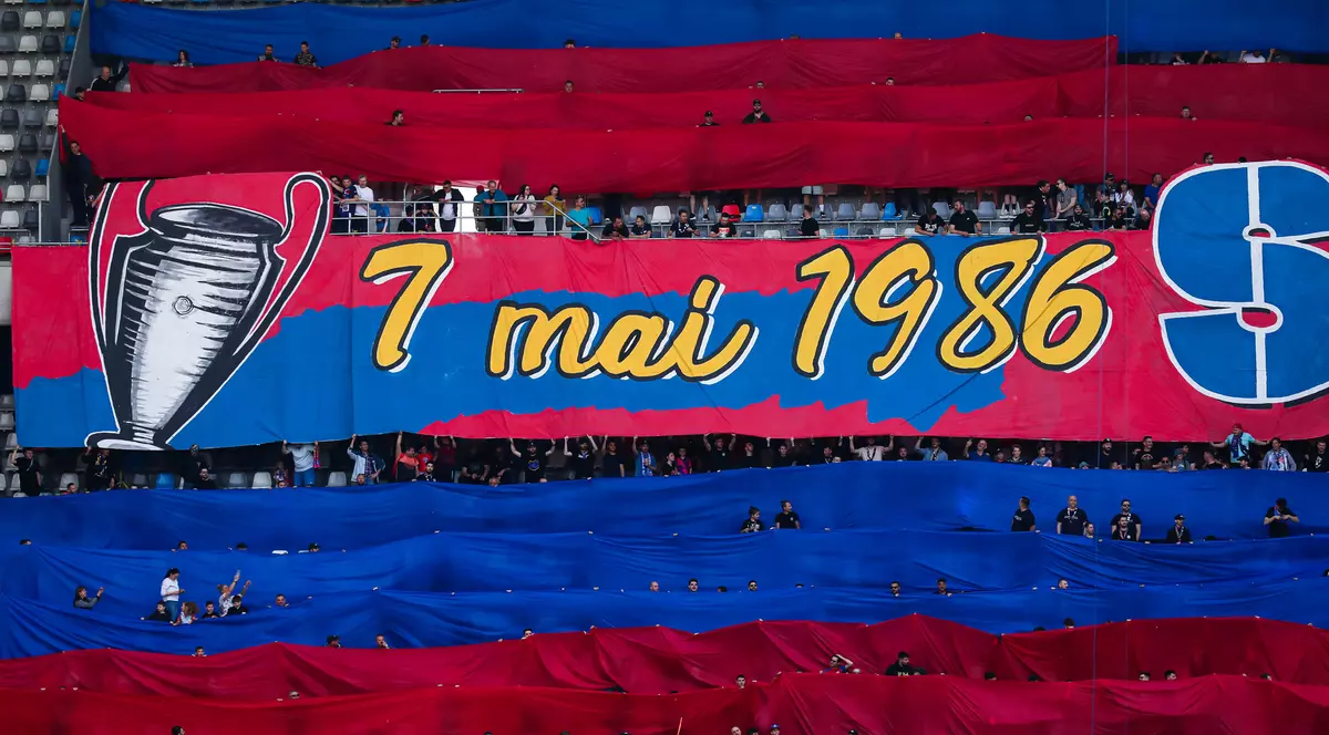 O imagine cu un banner roș albastru pe scare este imprimată Cupa Campionilor și data de 7 mai 1986.