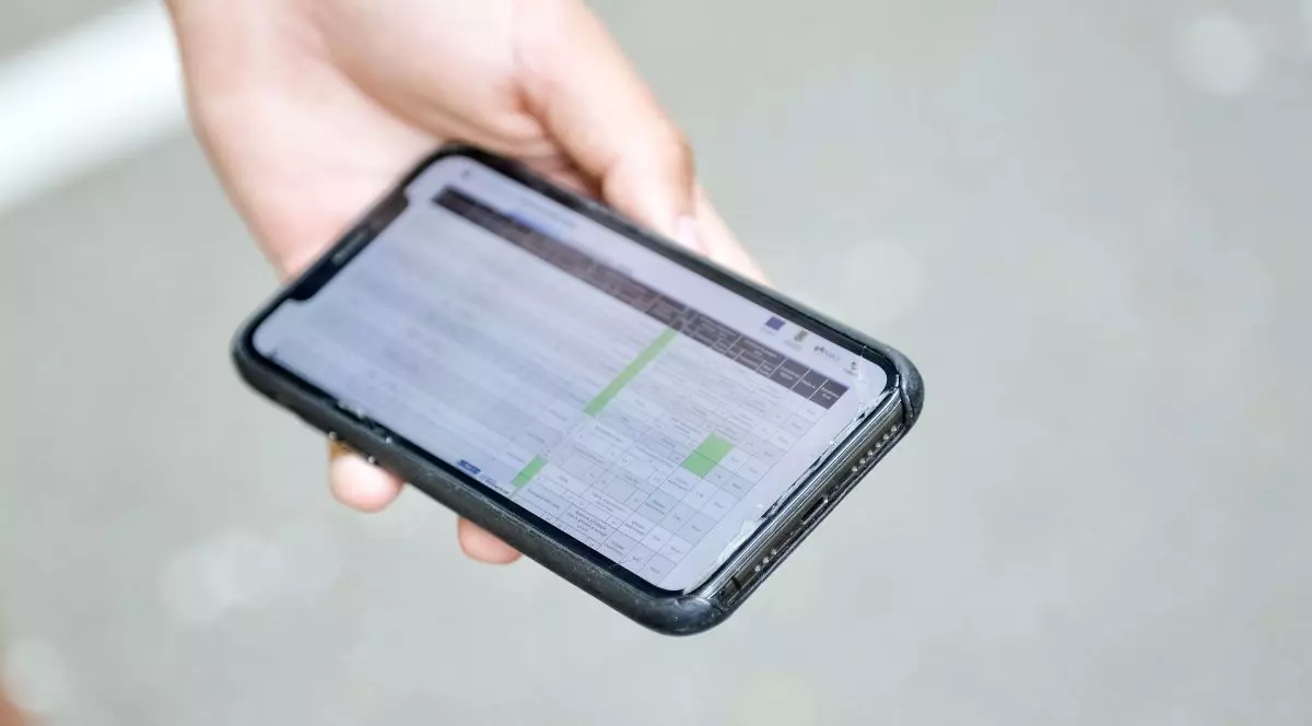 Un tânăr ține în mână un telefon mobil deschis pe site-ul Ministerul Educației unde verifică rezultatele examenului de Bacalaureat