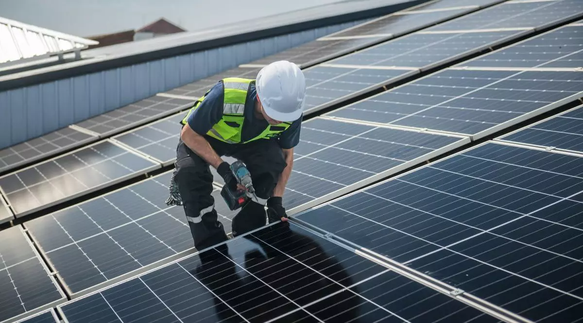 Un tehnician instalează panouri solare pe acoperișul unei fabrici pentru energie verde