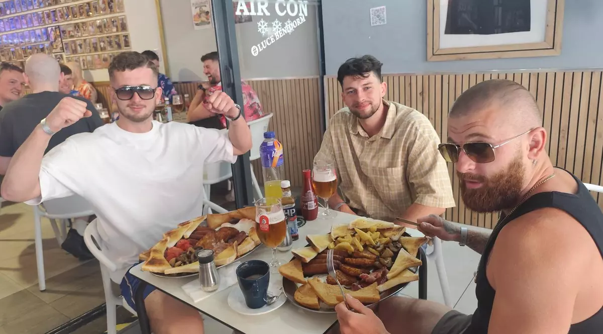Trei bărbați mănâncă la o masă, într-un restaurant, din Benidorm