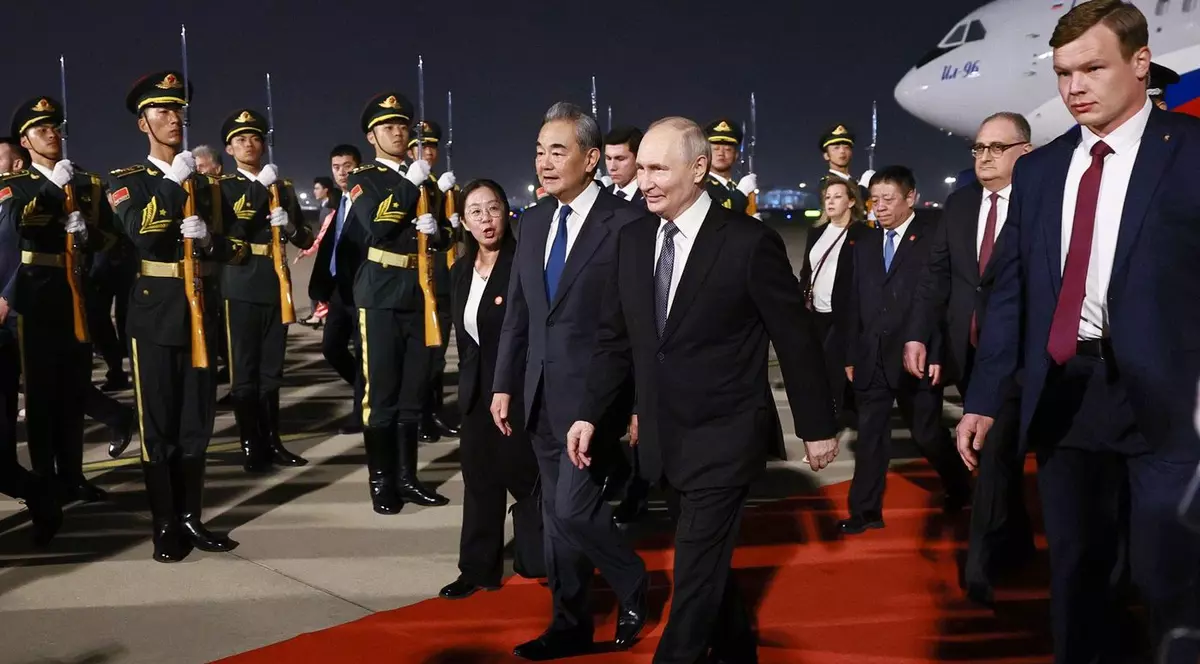 Vladimir Putin, cu zâmbetul pe buze după sosirea la Beijing, unde a fost întâmpinat de ministrul de Externe Wang Yi Foto: Profimedia